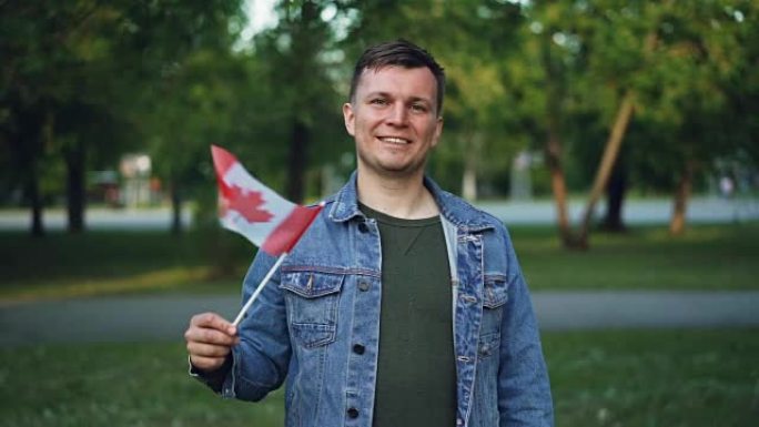 加拿大体育迷挥舞着加拿大支持国家运动队的旗帜，微笑着看着镜头，迷人的年轻人的慢动作肖像。