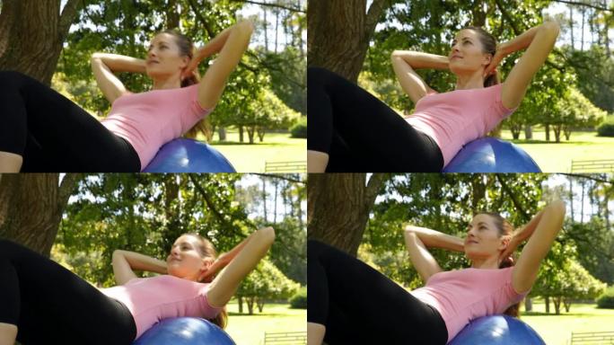 在公园做健身球仰卧起坐的健康女人