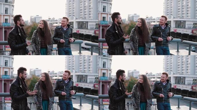 两个英俊的年轻男子和一个漂亮的女孩在桥上交谈。朋友聊天和微笑，在路上看到汽车。慢mo
