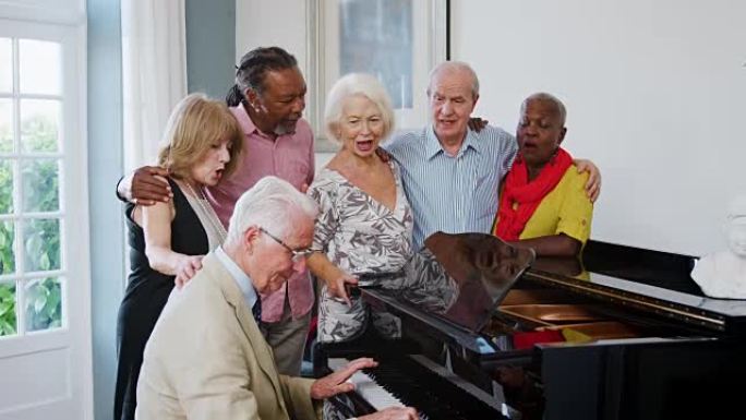 一群前辈站在钢琴旁一起唱歌