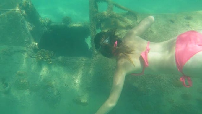 水下: 无法辨认的女性浮潜者看着沉没飞机的驾驶舱。