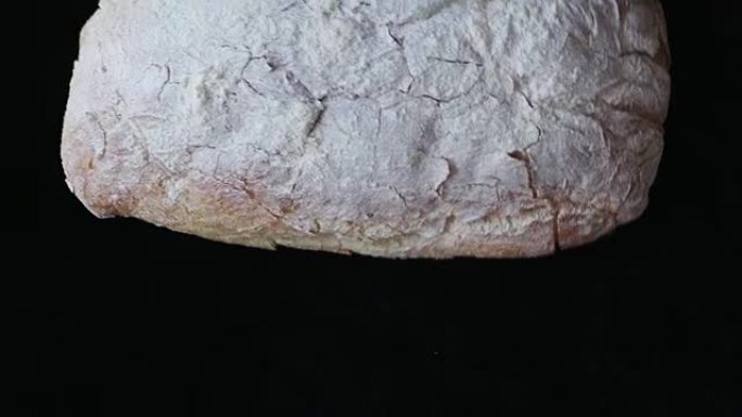 新鲜出炉的Ciabatta面包在黑色背景下掉落的慢动作