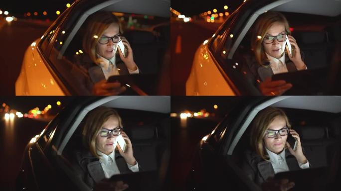 女商人在豪华轿车后座上使用数字平板电脑时在电话上聊天
