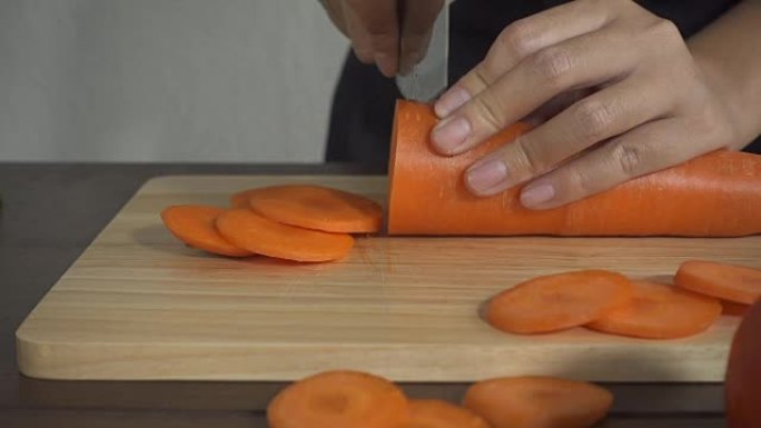 慢动作-女人在厨房的砧板上制作健康食品和切碎胡萝卜的特写镜头。