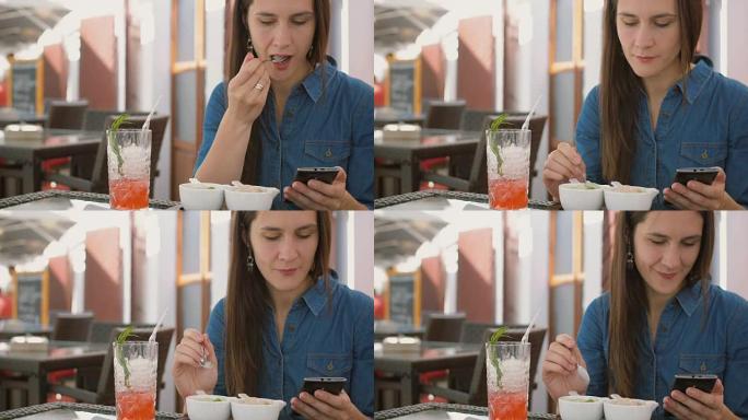 黑发女孩坐在咖啡馆外面吃冰淇淋时使用智能手机。全高清