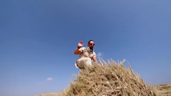 年轻的肌肉发达的人在沙丘上进行后空翻跳跃