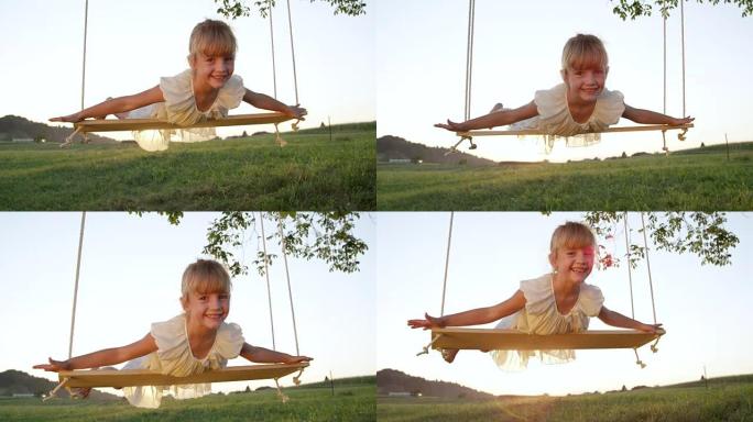 慢动作肖像: 快乐微笑的小女孩假装自己在秋千上飞翔