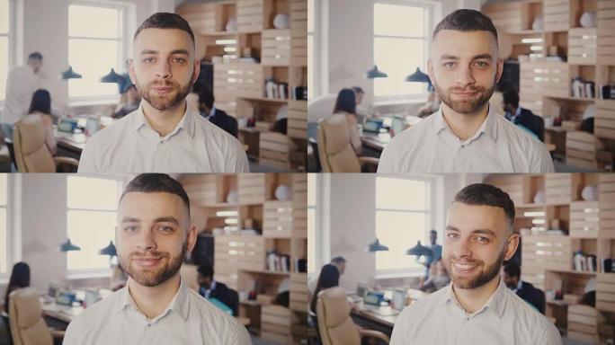 年轻快乐的白人商人在繁忙的办公室摆姿势的肖像。英俊的男性创意工作者看着4K相机