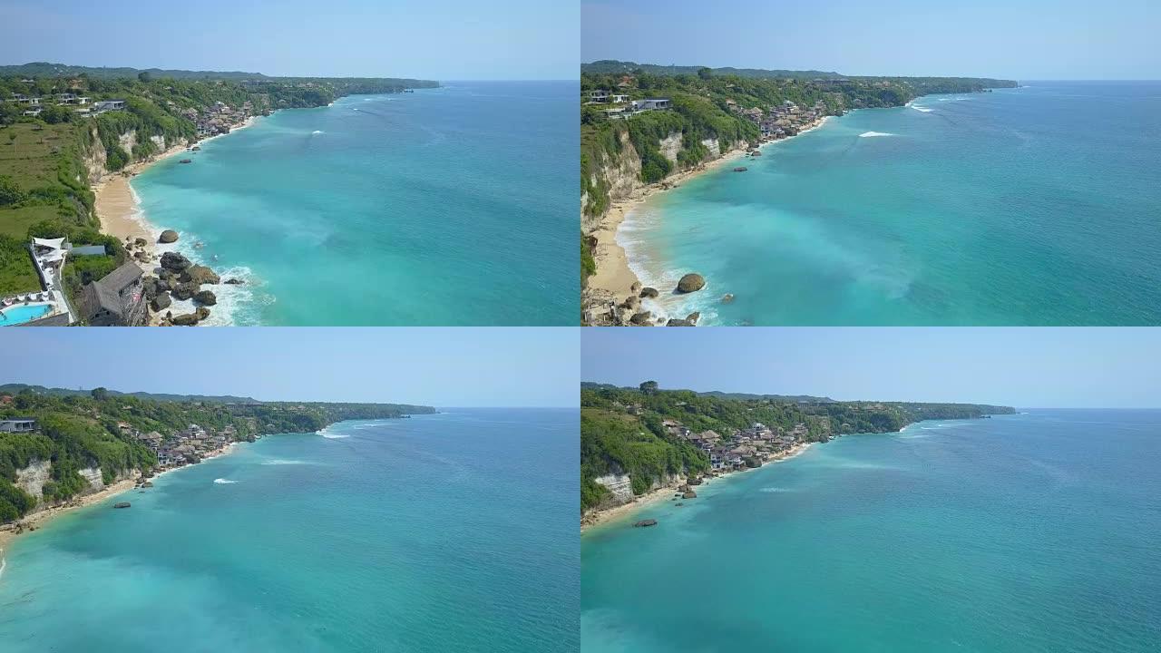在深蓝色海洋上方悬崖上的巴厘岛豪华度假村上空空中飞行