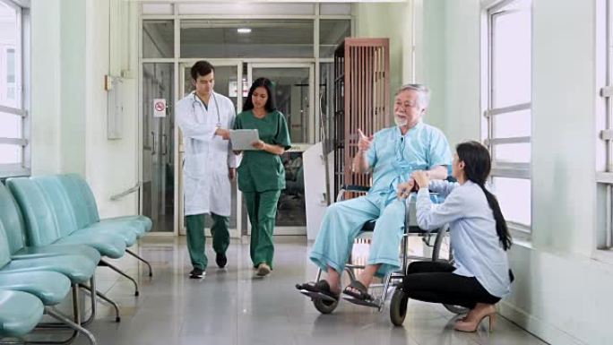 多种族的医务人员在繁忙的医院走廊里走动病人护理，女儿在医院为老年男性患者提供支持