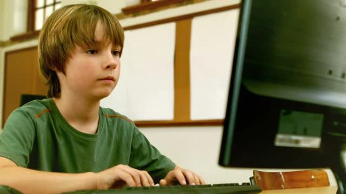 可爱的小学生在教室里看着笔记本电脑