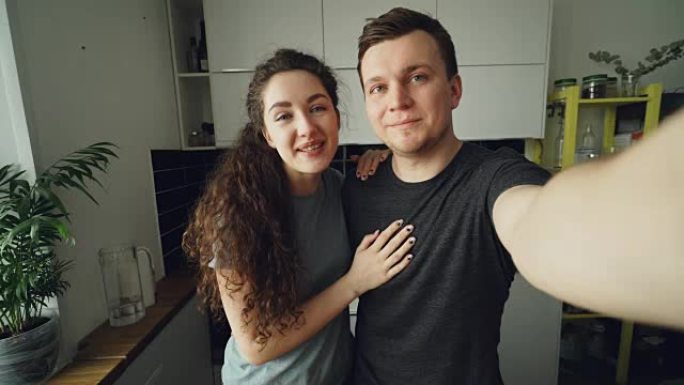年轻幸福的夫妇站在家里的厨房里用智能手机摄像头进行在线视频通话的视点