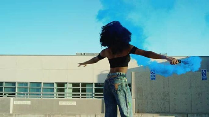 日落时分，年轻女子在屋顶停车场的烟雾手榴弹在外面跳舞