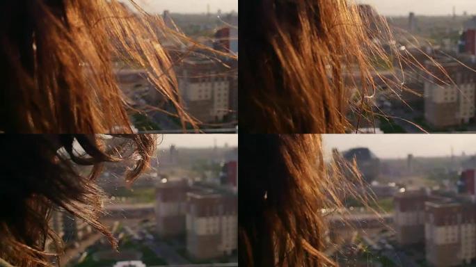 后视图。特写风吹起长长的黑发美丽的年轻女性。日落时站在屋顶上的女孩。慢mo