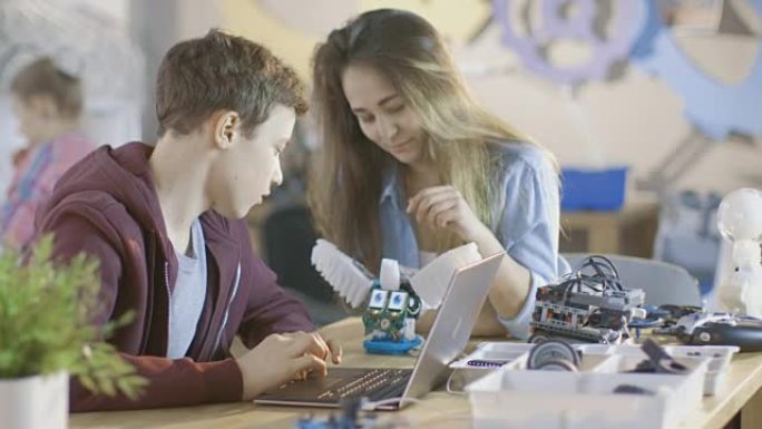 女孩和男孩在学校为他们的科学/机器人/工程课程提供带笔记本电脑的电子设备。