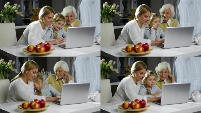 欢乐的妈妈，奶奶和小女孩在家里使用笔记本电脑