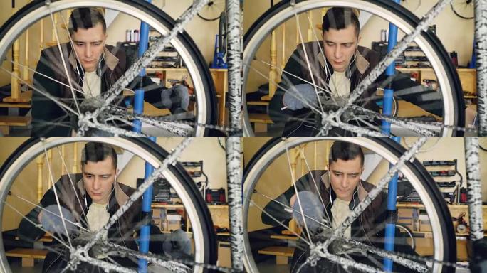 熟练的服务员正在修理自行车转弯踏板和旋转轮，用扳手拧紧接头将其固定。旋转的金属轮辐条处于前景。