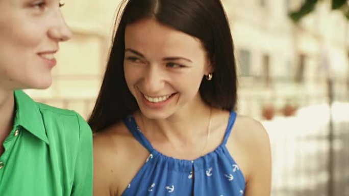 两个穿着浅色夏装的迷人年轻女性在欧洲小镇的街道上交谈。