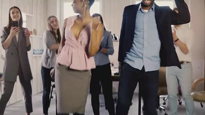两个非裔美国同事在办公室聚会上跳舞。混合种族朋友在工作场所4K有趣的活动