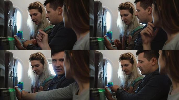 一群年轻漂亮的人坐在飞机上靠近窗户，用智能手机看旅行中的照片