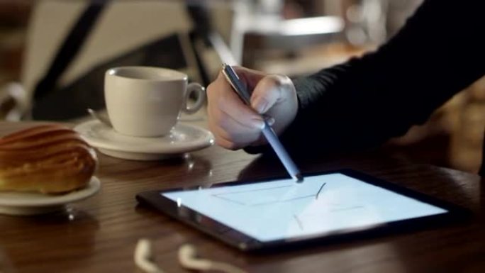 女人在咖啡店的平板电脑上画画