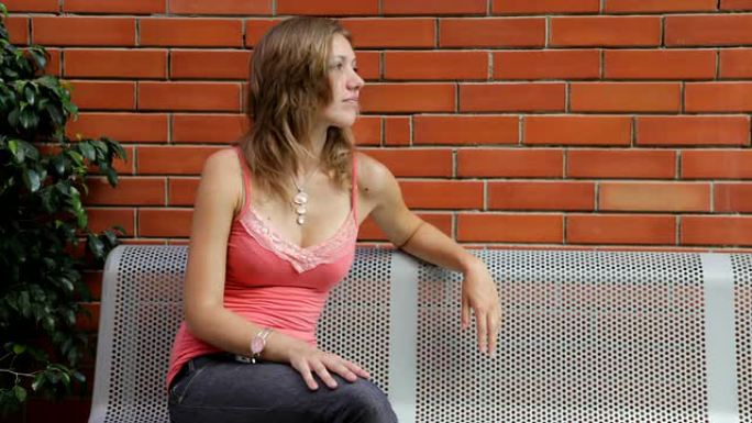 女孩坐在金属长椅上-红砖背景