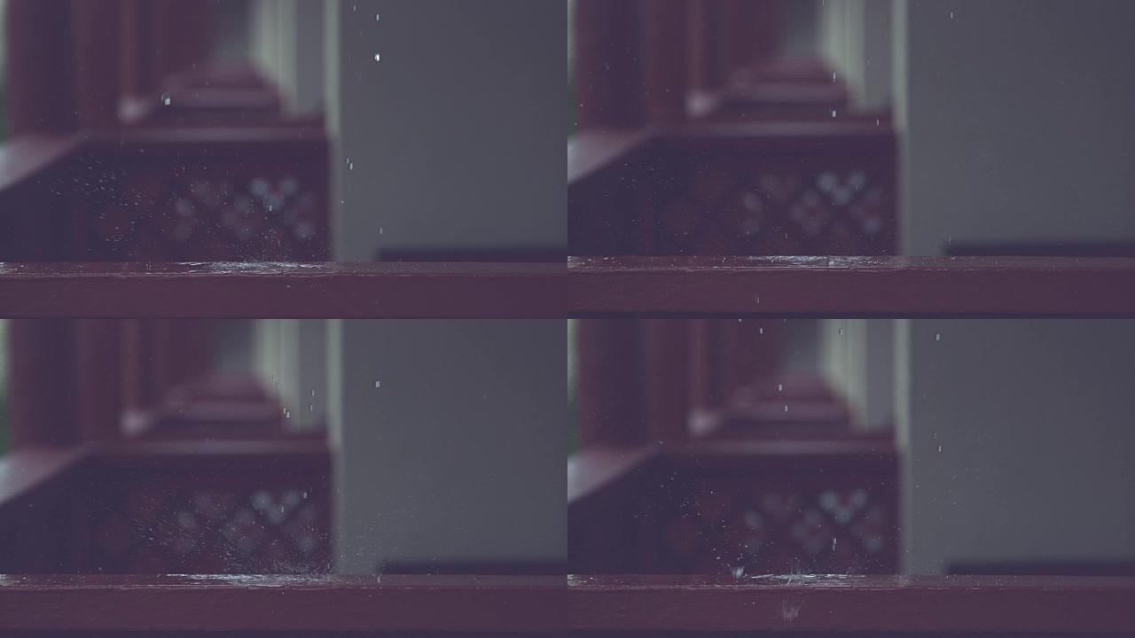 慢动作: 玻璃状雨滴落在木制栏杆上，并在门廊上飞溅