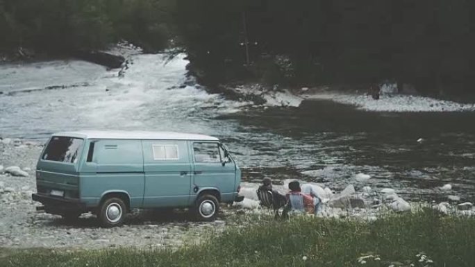 年轻夫妇在炉火旁放松。露营者在后台。山地景观