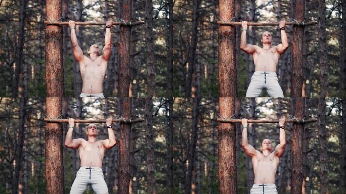 英俊的健美运动员在森林里做引体向上