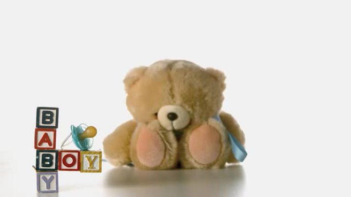 泰迪熊掉落在婴儿积木和蓝色安抚用品旁边