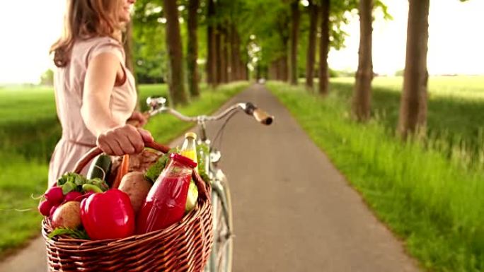 女人在公园里骑自行车和一篮子蔬菜