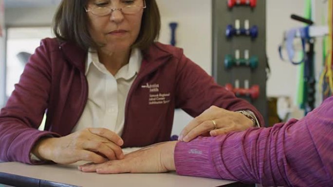 职业治疗师检查老年妇女手腕的活动性