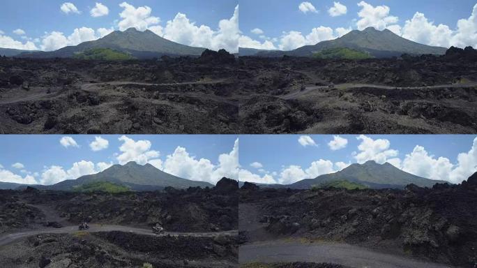 空中: 骑摩托车的人在黑色熔岩小径上行驶到巴图尔火山