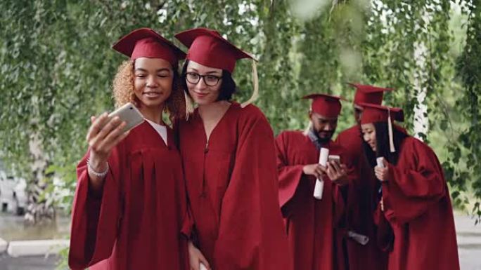 漂亮的年轻女性即将毕业的学生正在用智能手机自拍，然后看照片。现代技术、千禧一代和教育理念。