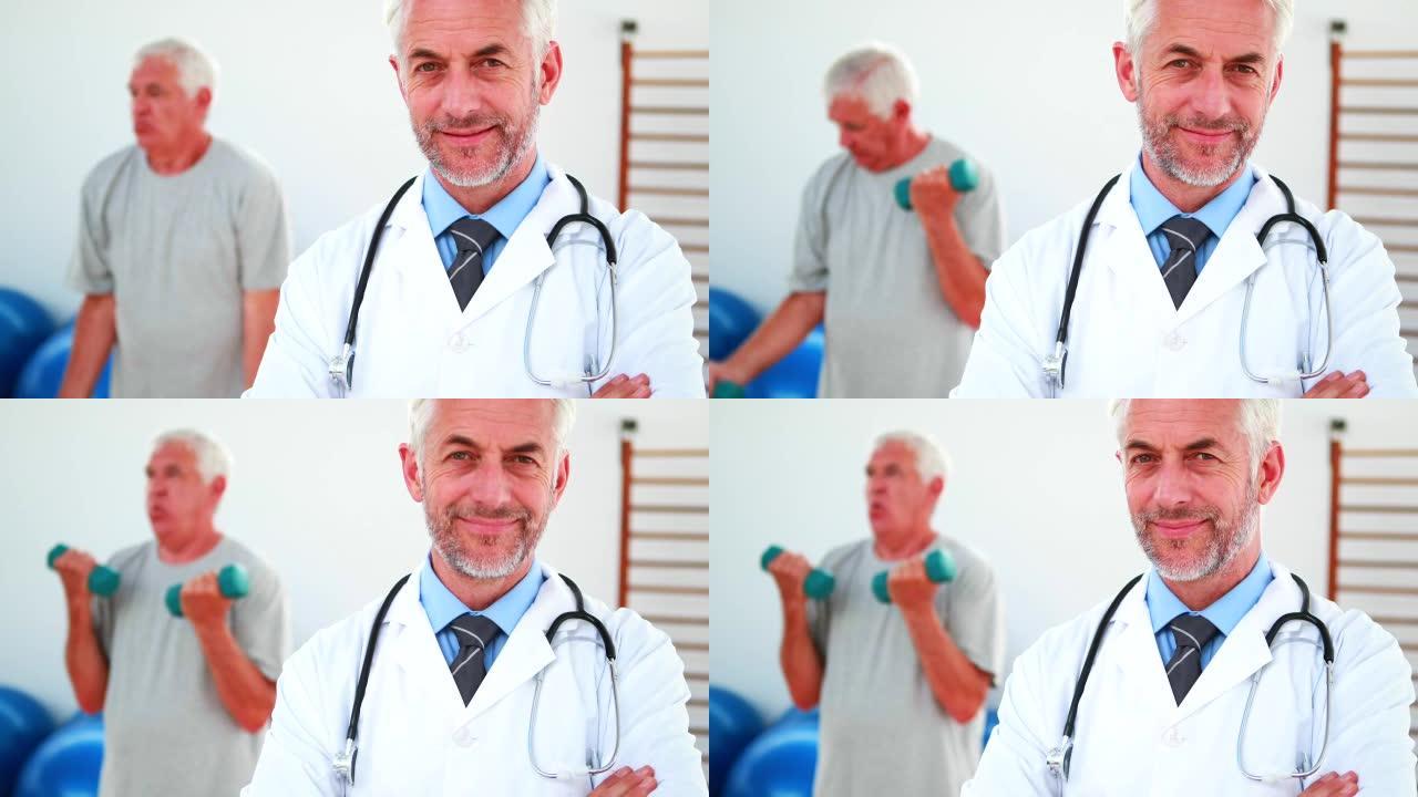 微笑的医生看着相机，病人在背景中锻炼