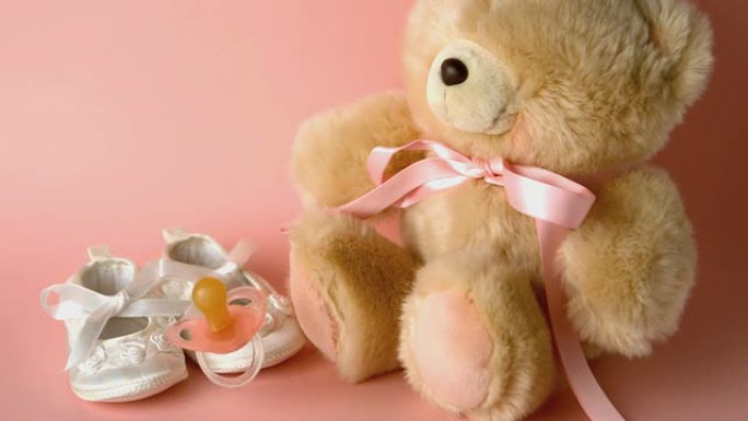 粉红色的sother落在婴儿鞋和泰迪面前