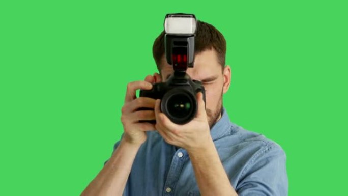 一位英俊的摄影师用相机拍照的特写镜头。在绿色屏幕上拍摄。