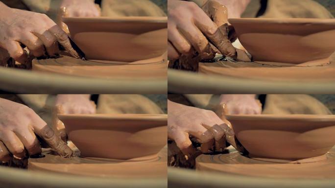 陶艺家手切掉碗中多余的粘土的详细视图。
