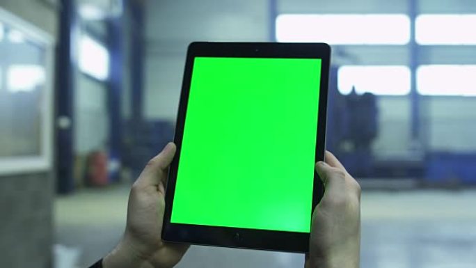 工厂工业环境中带有绿色模拟屏幕的平板电脑的镜头。
