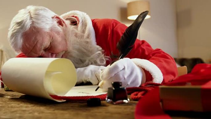 圣诞老人在用羽毛笔写信时睡在桌子上