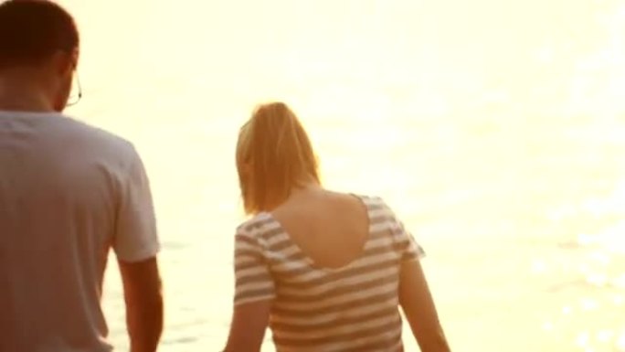 年轻的恋人男人和女人在日落时沿着湖边散步