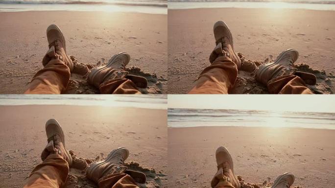 在沙滩上休息两只靴子的特写下，可以欣赏到美丽的柔和日落的景色