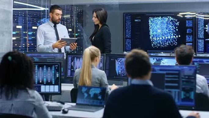 部门主管和项目经理使用平板电脑上的数据讨论工作过程。多民族团队构建具有集成机器学习的神经网络。