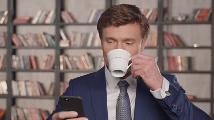 成功的有吸引力的商人使用智能手机应用程序和在办公室微笑喝茶的慢动作肖像。商人系列。