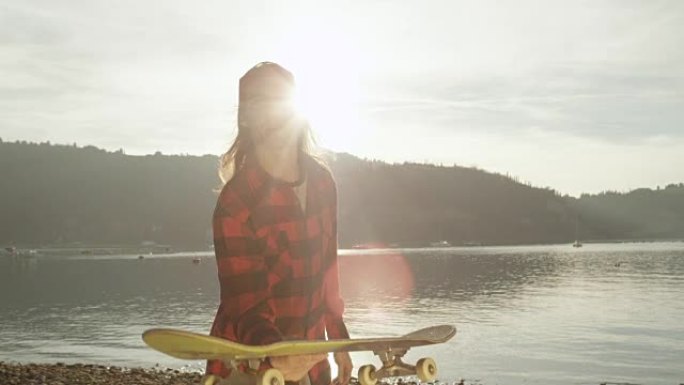 特写: 滑板手在日落时在海滩上向空中投掷滑板
