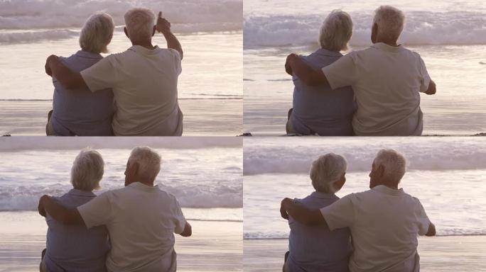 海滩上的高级夫妇的后视图观看海洋上的日落