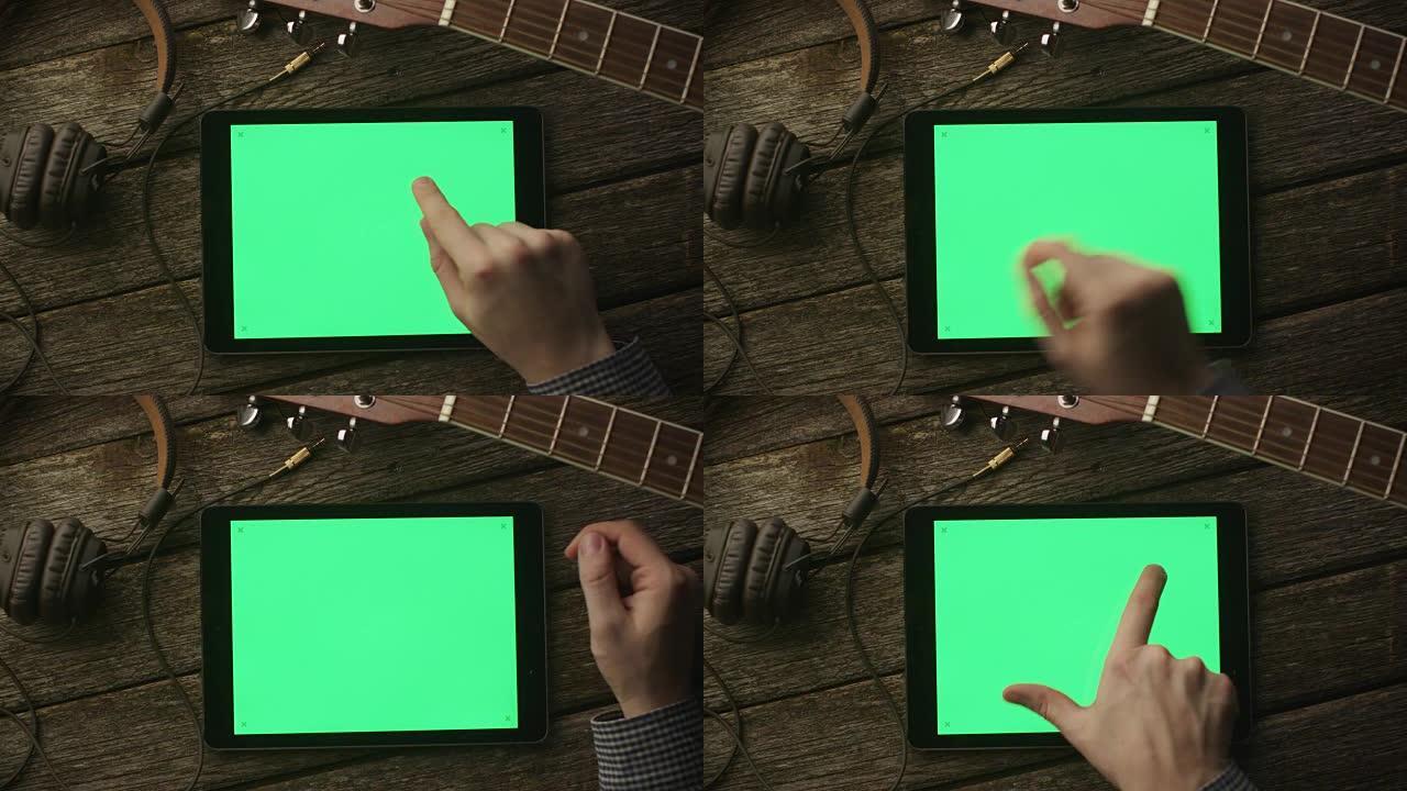 音乐家在横向模式下使用带绿屏的平板电脑。顶视图。因果生活方式