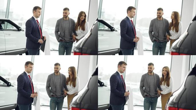专业的汽车推销员在车展上向感兴趣的买家介绍豪华汽车，而男人和女人正在看汽车并听经销商讲话。