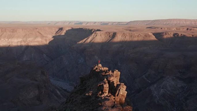 站在岩石顶峰上的男性游客的4k平移镜头拍摄鱼河峡谷