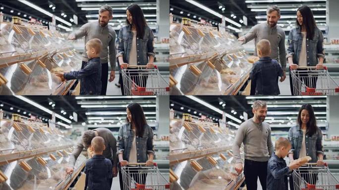 可爱的小男孩正在帮助他的父母在食品商店的面包店选择面包，他正在拿面包闻起来，然后放进购物车。